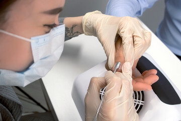 Young woman manicurist master is pushing cuticle on man's finger using pusher, closeup hands....