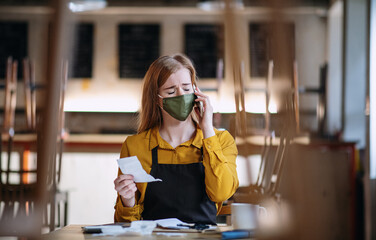 Frustrated owner sitting at table in closed cafe, small business lockdown due to coronavirus.