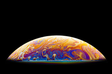 Isolate. Bright, iridescent patterns on the surface of the soap bubble.
