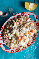 Bowl of traditional russian salad on blue wooden table. 