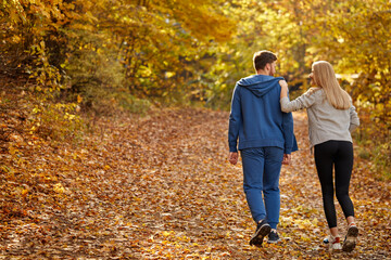 rear view on couple enjoying jogging on a country road through the beautiful autumn forest, exercise and fitness concept