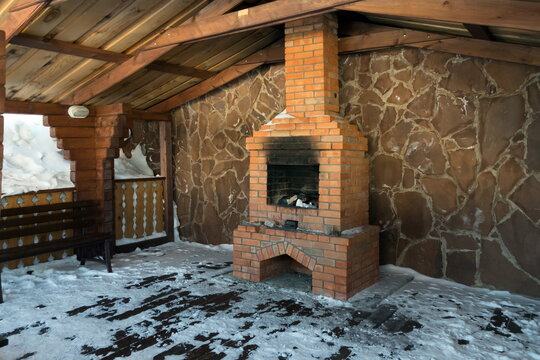A specially equipped place for winter recreation with a brick fireplace under the roof.
