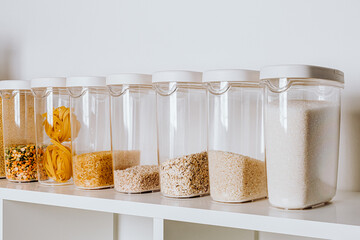 Stocked kitchen pantry with food - pasta, millet, oat flakes, peas, buckwheat, lentils, rice and...