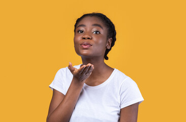 Pretty Black Woman Blowing A Kiss Posing On Yellow Background