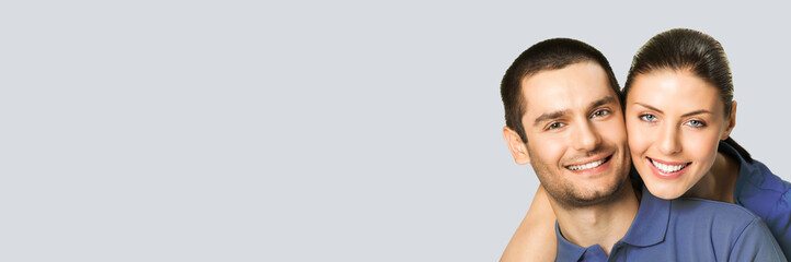 Love, relationship, lovers concept - studio portrait photo of happy smiling embracing couple, man and woman in piggyback pose, isolate over grey background. Copy space for text.