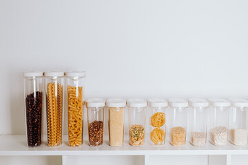 Stocked kitchen pantry with food - pasta, millet, oat flakes, peas, buckwheat, lentils, rice and...