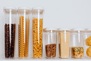 Stocked kitchen pantry with food - pasta, millet, oat flakes, peas, buckwheat, lentils, rice and...