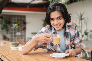 Portrait cheerful of young asian student enjoy drink coffee in a cafe.