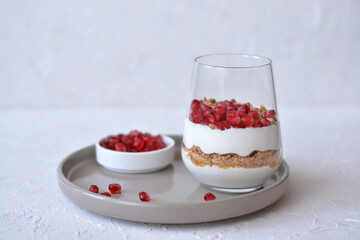 Tasty cheesecake with pomegranate in a glass on a white background. Cheesecake without baking. Dessert.
