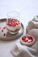 Tasty cheesecake with pomegranate in a glass on a white background. Cheesecake without baking. Dessert.