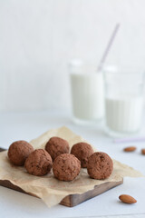 Energy balls. Homemade healthy raw energy balls with carob, figs decorated cocoa with glasses of milk on white background. Sugar free candies and  vegetarian truffles.