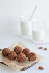 Energy balls. Homemade healthy raw energy balls with carob, figs decorated cocoa with glasses of milk on white background. Sugar free candies and  vegetarian truffles.