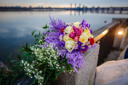 Wedding Bouquet of flowers on the railing of the bridge over the river.