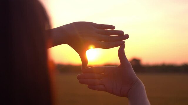 Future planning concept, Woman hands making frame gesture with sunset, Female capturing the sunrise.