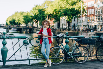 Optimistic lady with bicycle on embankment - obrazy, fototapety, plakaty