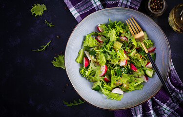 Fresh healthy salad of cucumbers, radishes and herbs with mustard-honey dressing. Top view, overhead