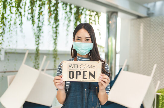 Asian Woman Wearing Mask Store Owner Holding CLOSED Sign In Front Door To Open The Shop Social Distancing New Normal.