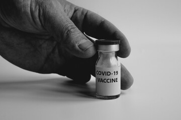 Negative or side effects of the coronavirus vaccine. Hand is holding a vial vaccine on black and white background. Healthcare and Medical concept for covid-19. A covid-19 coronavirus vaccination. 