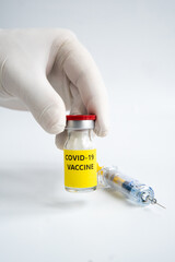 Hand with gloves is holding a vial vaccine and syringe. A covid-19 coronavirus vaccination concept. It use for prevention and immunization. Vertical vaccine concept on white background.