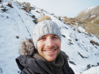 young guy in the snow looking and smiling. Sunny day