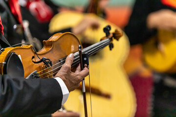 Selective focus of hands of senior man holding violin, and bow playing pizzicatos with orchestra...