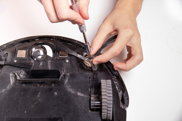 The master unscrews the robot vacuum cleaner brush to clean it.