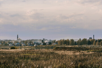 Fototapeta premium autumn evening landscape with a field and a river and a Christian Church on the horizon