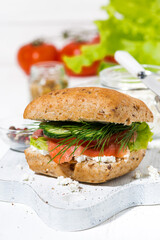sandwich with salted fish, fresh vegetebles and cream cheese on white wooden board, vertical closeup