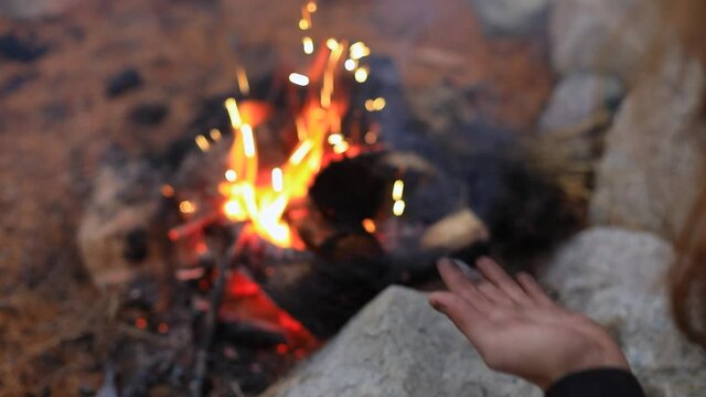 Selective focus of male hands blowing charcoal staff in sparkling bonfire while preparing for fire jamming event in forest in Canada