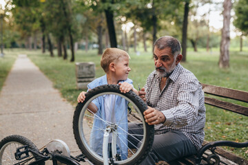 boy with his grandfather riding bike public park