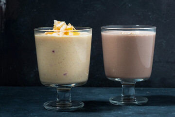 two servings of milkshake in glasses on dark background