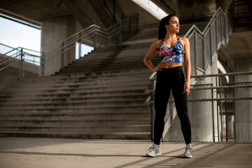 Young fitness woman taking a break from running in urban environment