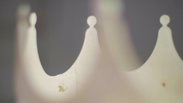 Close up of a beige crown peaks jagged spinning on a pedestal made out of plastic. With a neutral grey blurred background. Shot in 4K.