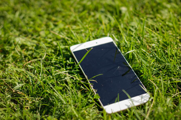 Mobile smart phone in green grass and black screen