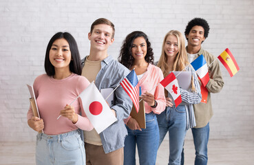 International multi-ethnic student exchange. Cheerful young people with devices and books look at...