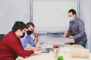 Businessmen wearing protective masks discussing and work together in meeting room. Social distance practice prevent coronavirus COVID-19.