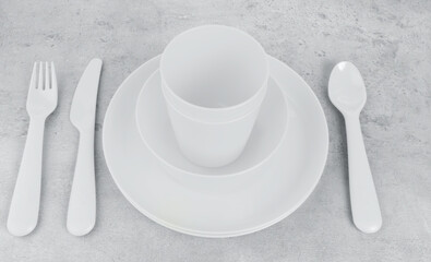 picnic cutlery utensils, plates, cups, fork, spoon and knife on toned grey background