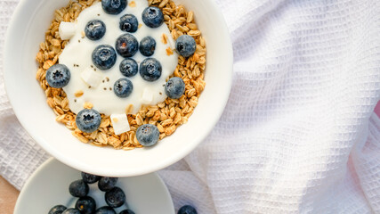 Delicious homemade muesli and blueberries served on a beige table with a white napkin, top view with space for text. Healthy breakfast