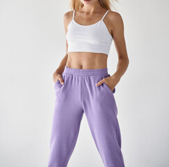 girl wears violet pants with white top crop. fit woman standing in casual clothes