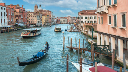 gondola and tourist ships sailing along the Grand Canal in Venice against the backdrop of beautiful houses and blue sky © westermak15