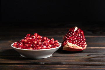 Garnet seeds and cracked pomegranate on wooden background