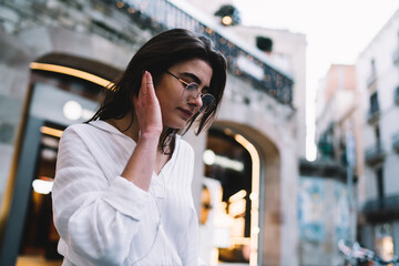 Pensive woman listening to music on street