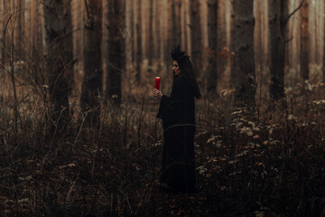 dark terrible witch with candles in her hands performs an occult mystical ritual