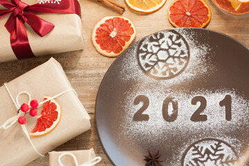 Christmas and New Year 2021 background with a festive plate with the inscription 2021 and boxes of gifts

