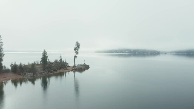 Aerial drone passing Tubbs Hill tree in the fog in Coeur d'Alene Idaho