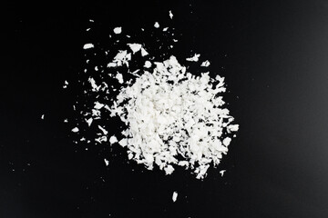 a pile of poured white artificial synthetic snow on a black background