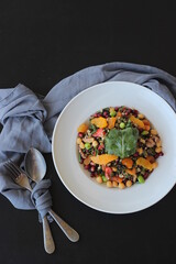 mixed grain salad with oranges on a white plate on a black table