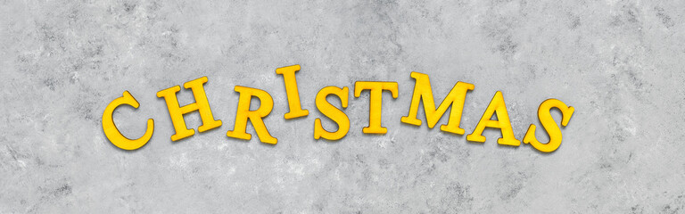 Yellow word Christmas on gray grunge background. The trendy 2021 color combination is gray and yellow. Banner.