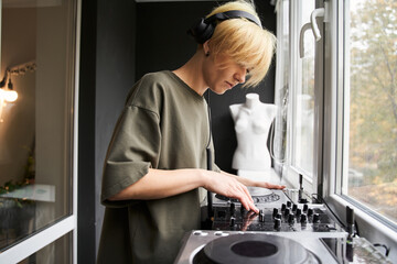 Female musician wearing headphones making hip hop beats