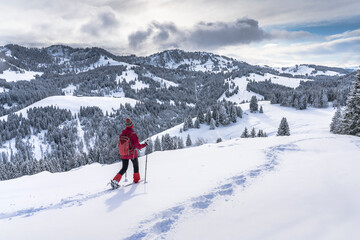 nice and active senior woman snowshoeing in deep powder snow in the Allgau alps, Bavaria, Germany